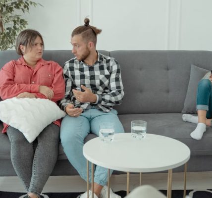 A family therapy session with parents discussing things while a child is absorbed in her smartphone.