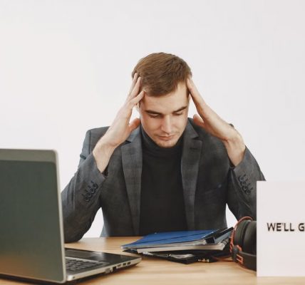 Young man in home office feeling stressed, working during pandemic with motivational message by his side.